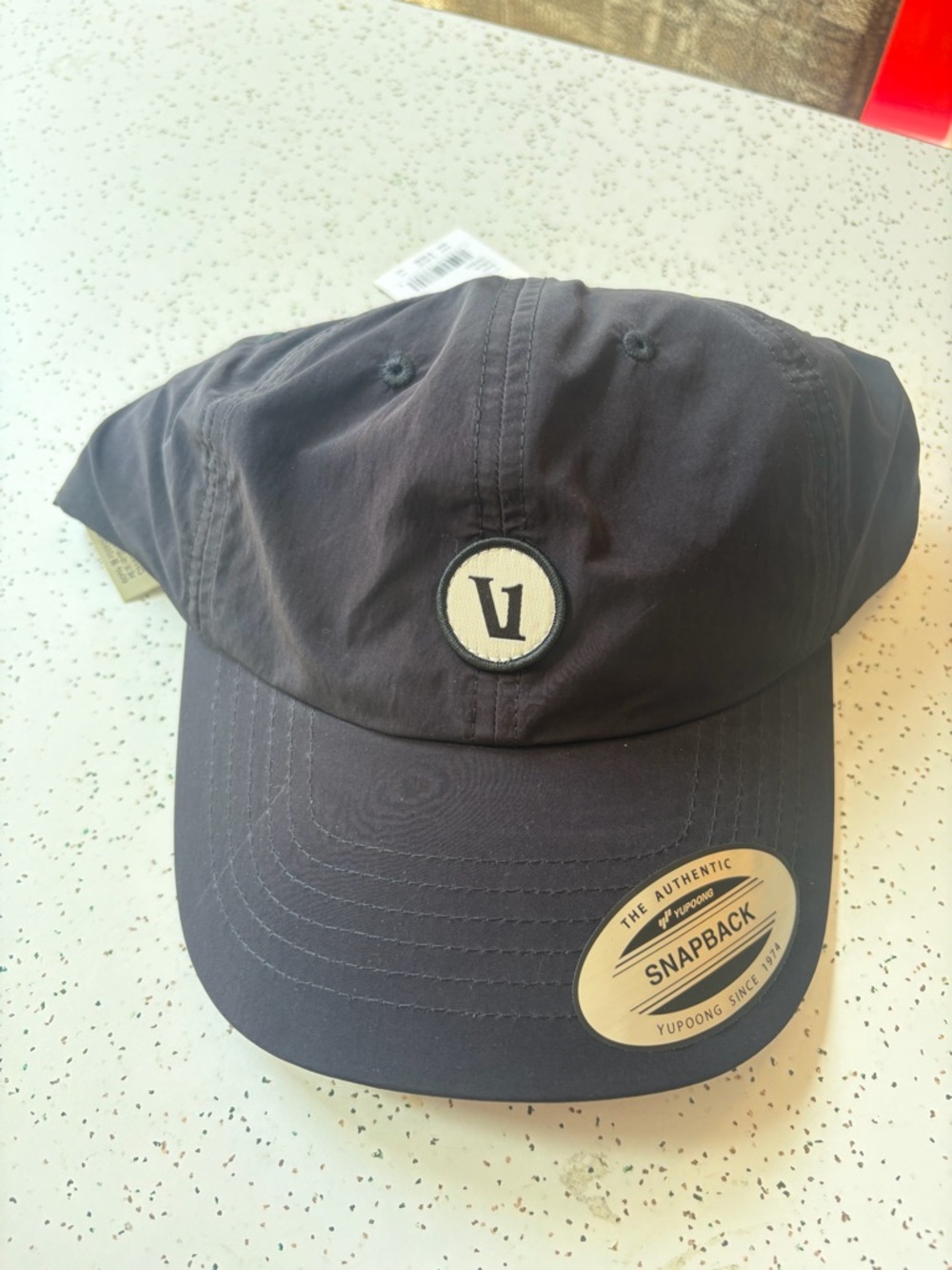 Vuori Black Snapback Cap with Cream Logo Patch